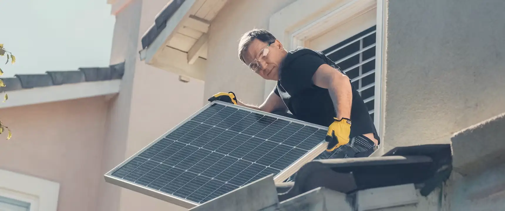 a person with a pair of yellow gloves installing a solar panel