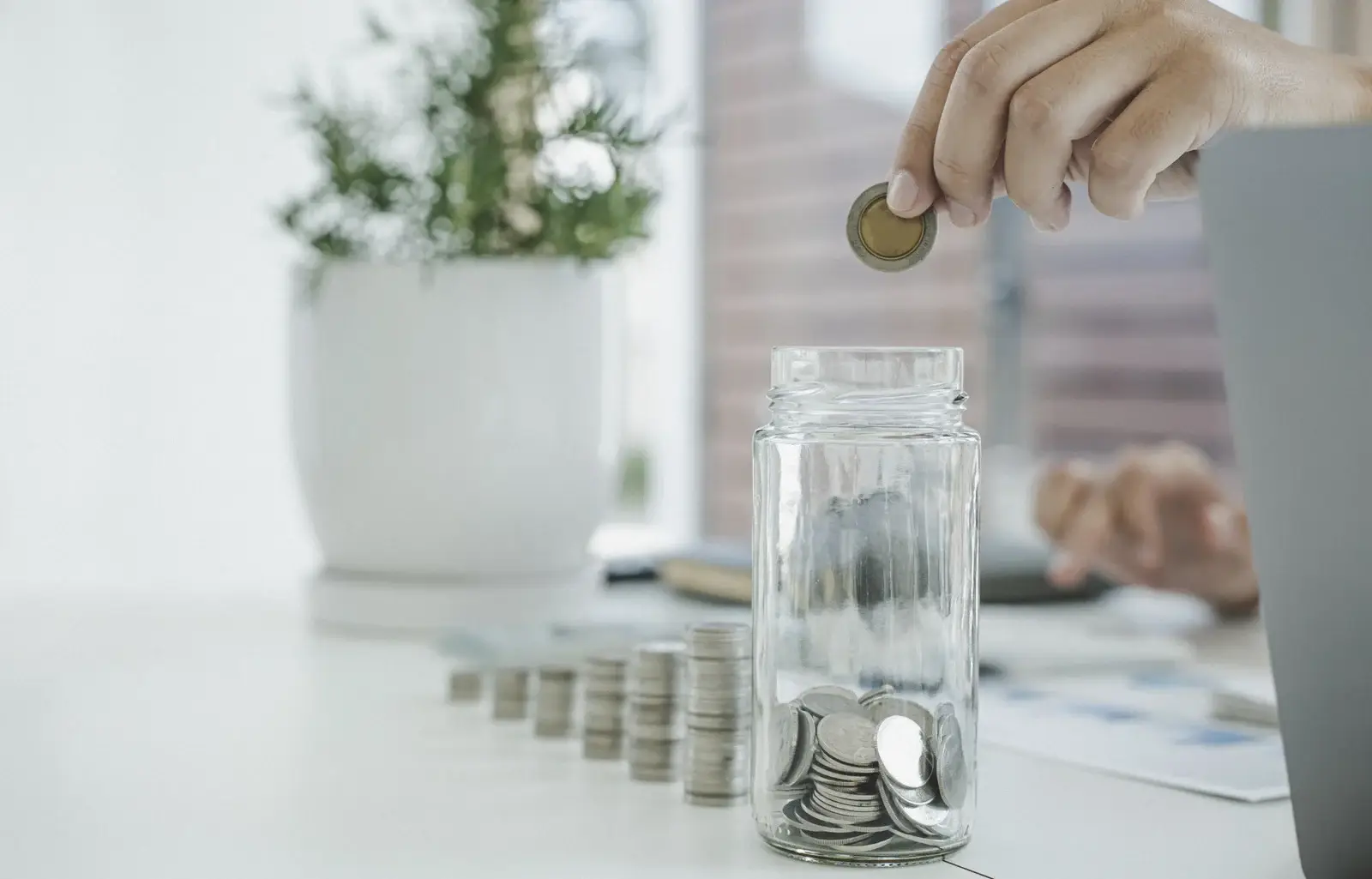 a person holding puting a coin in a glass - financial benefits